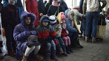 Des enfants assis à la gare de Lviv, en Ukraine, alors que des personnes montent dans des trains d'évacuation vers la Pologne,&nbsp;le 28 février 2022. (MARKIIAN LYSEIKO / NURPHOTO / AFP)