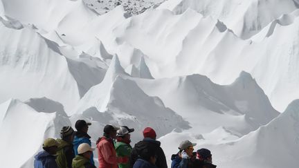 Des N&eacute;palais membres d'une exp&eacute;dition observe un h&eacute;licopt&egrave;re qui emporte des bless&eacute;s, au camp de base de l'Everest, dimanche 26 avril 2015.&nbsp; (ROBERTO SCHMIDT / AFP)