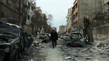 Un homme marche dans une rue de Douma dans la Ghouta orientale (Syrie), le 25 février 2018. (HAMZA AL-AJWEH / AFP)