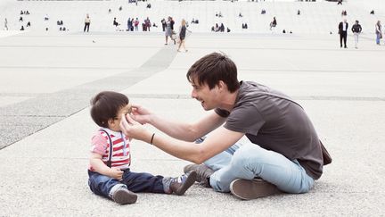  (Un père met des lunettes de soleil à son jeune fils  © Maxppp)