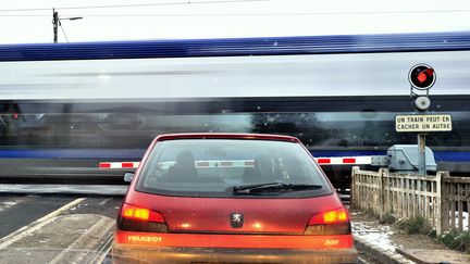 Une voiture arrêtée devant un passage à niveau alors qu'un TER circule, à Flêtre (Nord), le 14 janvier 2013. (PHILIPPE HUGUEN / AFP)