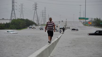 A Houston, cet automobiliste a abondonné sa voiture prise au piège des eaux et poursuit son trajet à pied. (NICK OXFORD / REUTERS)