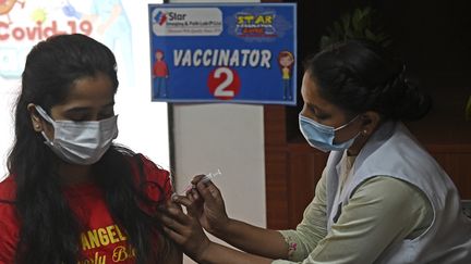 Une soignante administre une dose de vaccin contre le Covid-19 à une patiente à New-Delhi (Inde), le 10 avril 2022. (MONEY SHARMA / AFP)