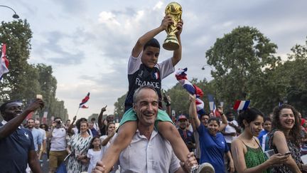 Un père et son fils célèbrent la victoire de l'équipe de France de football à la Coupe du monde, le 15 juillet 2018, sur les Champs-Elysées, à Paris. (PASCAL SONNET / HANS LUCAS / AFP)