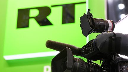 Une caméra devant le logo de la chaîne RT, le 24 mai 2018 à Saint-Pétersbourg (Russie). (KIRILL KUDRYAVTSEV / AFP)