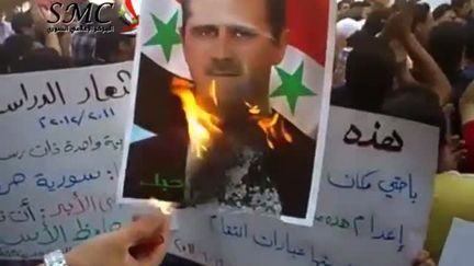 Lors d'une manifestation &agrave; Damascus en Syrie, le 19 septembre, un manifestant br&ucirc;le un portrait du pr&eacute;sident Bachar Al-Assad.&nbsp; (YOUTUBE/AFP)