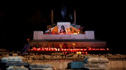 Un homme dispose des bougies et des fleurs au pied du mémorial érigé en mémoire de la journaliste d'investigation maltaise&nbsp;assassinée Daphne Caruana Galizia, le 16 novembre 2018 à La Valette, à Malte. (DARRIN ZAMMIT LUPI / REUTERS)