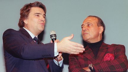 L'industriel Bernard Tapie fait un discours, en compagnie de son conseiller en communication Jacques Seguela, le 12 décembre 1992 à Marseille, à l'occasion du recrutement de la 3000e élève des écoles de vente "Bernard Tapie". (ERIC CABANIS / AFP)