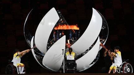 Les athlètes Karin Morisaki, Yui Kamiji et Shunsuke Uchida ont eu la mission d'allumer&nbsp;ensemble la vasque paralympique lors de la&nbsp;cérémonie d'ouverture, tenue à&nbsp;huis clos mais en présence de 3 400 athlètes. Au même moment, le Japon enregistrait sa pire vague&nbsp;du coronavirus sous l'effet du variant Delta. L'absence des athlètes néo-zélandais ou encore la réduction de la délégation brésilienne rappelaient l'enjeu de la situation sanitaire. (PHILIP FONG / AFP)