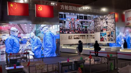 Des visiteurs prennent part à une exposition mettant en scène la gestion de l'épidémie de Covid-19 à Wuhan (Chine),&nbsp;dans l'un des anciens hôpitaux de fortune construits pendant la crise sanitaire, le 15 janvier 2021. (NICOLAS ASFOURI / AFP)