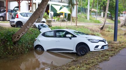 Une voiture coincée dans un fossé inondé, dans la commune du Gosier (Guadeloupe), le 30 avril 2022. (CEDRICK ISHAM CALVADOS / AFP)