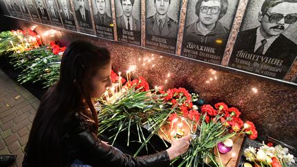 Une jeune femme allume une bougie près du monument en hommage aux victimes de la catastrophe, à&nbsp;Slavutych (Ukraine), le 26 avril 2019. (GENYA SAVILOV / AFP)