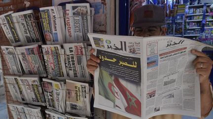 Un Algérien lit un journal devant un kiosque&nbsp;à Alger, le 25 août 2021. (RYAD KRAMDI / AFP)