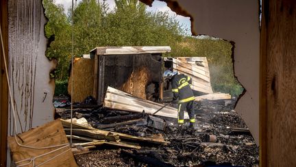 Un pompier intervient dans le camp de migrants de Grande-Synthe, mardi 11 avril 2017, au lendemain de l'incendie qui a ravagé les lieux. (PHILIPPE HUGUEN / AFP)