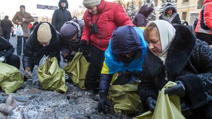 Des femmes ramassent des pierres, le 23 janvier 2014, &agrave; Kiev. (VOLODYMYR SHUVAYEV / AFP)