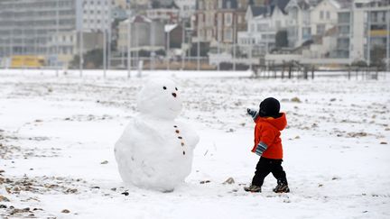 Un enfant s'approche d'un bonhomme de neige sur la plage du Havre (Seine-Maritime), le 13 janvier 2010. (MAXPPP)