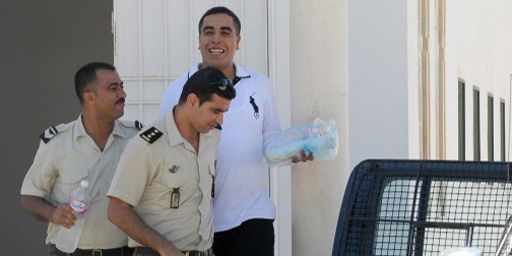Le rappeur Klay BBJ (Ahmed Ben Ahmed) est escorté par des policiers à sa sortie du tribunal de Hammanet (60 km au sud de Tunis), le 26 septembre 2013. (AFP - Fethi Belaid)