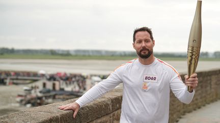 Thomas Pesquet porte la flamme olympique au Mont-Saint-Michel, lors du relais de la flamme, le 31 mai 2024. (LAURENT VU / PARIS 2024 / AFP)