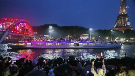 Le public regarde la délégation française défiler sur la Seine, lors de la cérémonie d'ouverture des JO de Paris, le 26 juillet 2024. ((HERVIO JEAN-MARIE / KMSP via AFP))