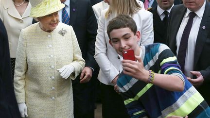 Un jeune gar&ccedil;on tente de faire un selfie avec la reine Elizabeth d'Angleterre lors de sa visite du march&eacute; St George &agrave; Belfast (Irlande du Nord), le 24 juin 2014. (PETER MACDIARMID / AFP)