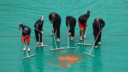 Des employ&eacute;s &eacute;vacuent l'eau de pluie du court Philippe Chatrier lors de l'open de tennis de Roland-Garros &agrave; Paris, le 28 mai 2013. (JULIAN FINNEY / GETTY IMAGES)