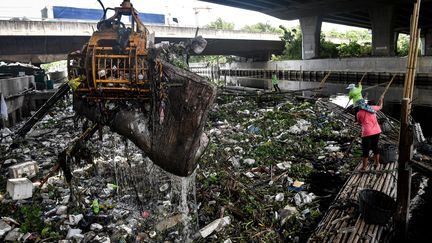 Des employés municipaux de Bangkok transfèrent des déchets depuis un canal vers un camion à déchets, le 9 juin 2020. (LILLIAN SUWANRUMPHA / AFP)