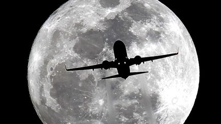 Un avion passe devant la pleine lune pr&egrave;s de l'a&eacute;roport de Los Angeles (Californie, Etats-Unis), le 15 janvier 2014. (NICK UT / AP / SIPA)