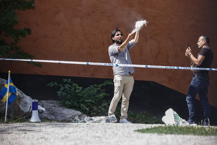 Salwan Momika brûle des pages d'un coran lors de sa première action, devant la grande mosquée de Stockholm (Suède), le 28 juin 2023. (STEFAN JERREVANG / TT NEWS AGENCY / AFP)