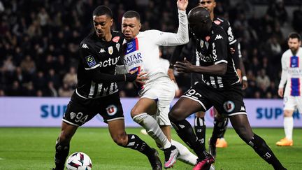 Kylian Mbappé au contact avec deux Angevins lors du match de Ligue 1 entre Angers et le PSG, le 21 avril 2023. (JEAN-FRANCOIS MONIER / AFP)