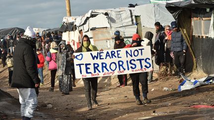 Deux hommes ont improvisé une manifestation en marge du démantèlement, avec une pancarte "Nous ne sommes pas des terroristes, donc ne détruisez pas nos maisons". (PHILIPPE HUGUEN / AFP)