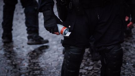 Un policier tient à la main une grenade GLI-F4, lors d'une manifestation des "gilets jaunes", sur la place de la Bastille, à Paris, le 26 janvier 2019.&nbsp; (KARINE PIERRE / HANS LUCAS / AFP)