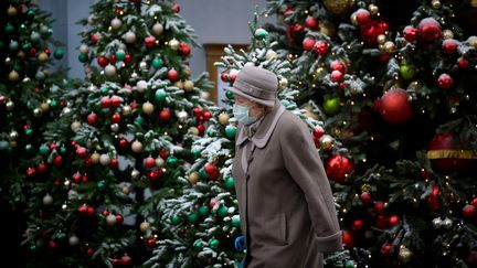 Une femme porte un masque devant des sapins de Noël, le 1er décembre 2020 à Moscou (Russie). (NATALIA KOLESNIKOVA / AFP)