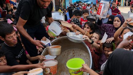 Des enfants palestiniens reçoivent de la nourriture dans une école gérée par l'ONU à Rafah, dans le sud de la bande de Gaza, le 23 octobre 2023. (MOHAMMED ABED / AFP)