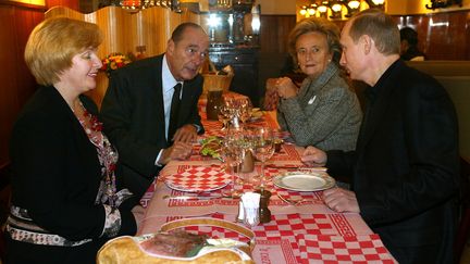 Le chef de l'Etat vante aussi les mérites de la gastronomie française à ses homologues, comme ici, lors de la visite du président russe Vladimir Poutine et de son épouse, en 2003. (PATRICK KOVARIK / AFP)