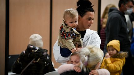 Une femme tient son enfant dans les bras dans un centre d'accueil pour réfugiés à Paris, le 17 mars 2022. (ALAIN JOCARD / AFP)