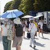 Des touristes équipées d'un parapluie et de chapeaux se protègent du soleil durant les Jeux olympiques, à Paris, le 30 juillet 2024. (LAURE BOYER / HANS LUCAS / AFP)