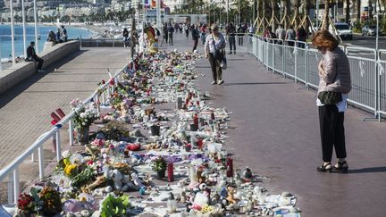 Le 10 octobre, une femme regarde les fleurs déposées sur la promenade des Anglais à Nice en hommage aux victimes de l'attentat du 14 juillet. (CITIZENSIDE/JEAN-LUC THIBAULT / AFP)