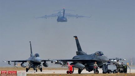 Deux F16 de l'armée américaine sont stationnés alors qu'un C17 décolle du tarmac d'une base italienne, le 25 mars 2011. (AFP - Giuseppe Cacace)