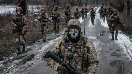 Des militaires ukrainiens marchent sur la route menant à leur base près de la ligne de front dans la région de Donetsk, le 4 février 2023. (YASUYOSHI CHIBA / AFP)