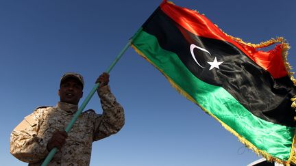 Un membre des forces opposées au gouvernement d'union agite un drapeau libyen à Zuwetina (Libye) en septembre 2016 (ABDULLAH DOMA / AFP)