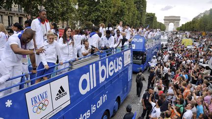 Du haut de leurs trois bus &agrave; imp&eacute;riale, les champions fran&ccedil;ais saluent la foule mass&eacute;e derri&egrave;re les barri&egrave;res.&nbsp; (MEHDI FEDOUACH / AFP)