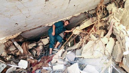 Un homme cherche des survivants dans les décombres des habitations de Derna, le 14 septembre en Libye, après les inondations meurtrières qui ont touché l'est du pays. (ABDULLAH DOMA / AFP)