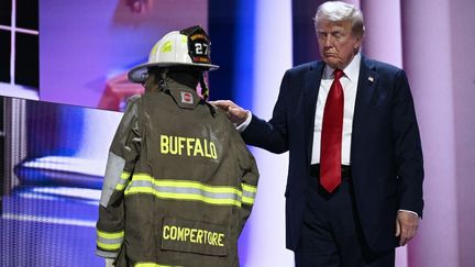 Au dernier jour de la convention républicaine, le 18 juillet 2024, Donald Trump pose sa main sur une personne portant la veste de pompier de Corey Comperatore, tué lors du meeting du candidat républicain de samedi dernier, en Pennsylvanie. (BRENDAN SMIALOWSKI / AFP)