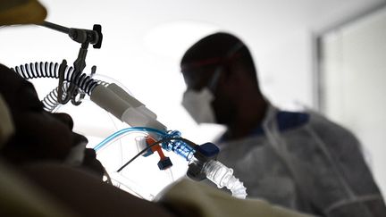 Un soignant&nbsp;au chevet d'un patient hospitalisé en réanimation, le 8 mars 2021 à Boulogne-Billancourt (Hauts-de-Seine). (ALAIN JOCARD / AFP)