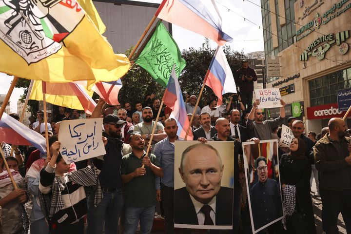 Des Palestiniens à Hébron en Cisjordanie portent des drapeaux du Fatah et du Hamas, et le portrait de Vladimir Poutine, le 20 octobre 2023. (HAZEM BADER / AFP)