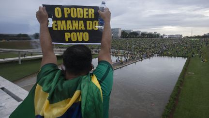 Un émeutier à Brasilia, le 8 janvier 2023. Sur son écriteau, "O poder emana di povo", "Le pouvoir émane du peuple". Ils contestent l'élection de Lula face à Jair Bolsonaro et demandent une intervention de l'armée pour le démettre. (JOEDSON ALVES / ANADOLU AGENCY VIA AFP)