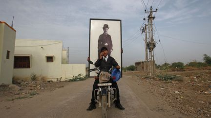 Deux hommes transporte un portrait de Charlie Chaplin dans une rue d'Adipur (Inde), en marge des c&eacute;l&eacute;brations de l'anniversaire de l'acteur britannique, le 16 avril 2012. (DANISH SIDDIQUI / REUTERS)