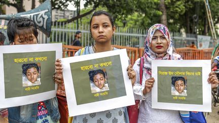 Des femmes brandissent des photos&nbsp;de Nusrat Jahan Rafi, une&nbsp;étudiante brûlée vive, le 12 avril 2019, à&nbsp;Dacca (Bangladesh). (SAZZAD HOSSAIN / AFP)