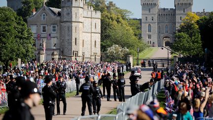 Des spectateurs se massent le long de l'allée qui mène au chateau de Windsor avant le mariage entre le prince Harry et Meghan Markle, le 19 mai 2018. (TOLGA AKMEN / AFP)