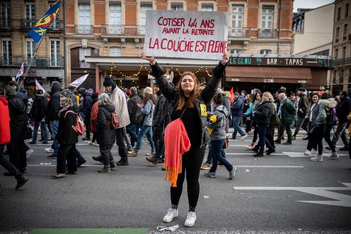 Une manifestante brandit une pancarte à Toulouse durant la manifestation du 19 janvier 2023 contre la réforme des retraites.&nbsp; (LIONEL BONAVENTURE / AFP)